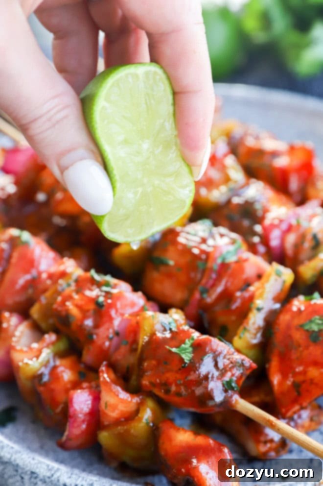 Hand squeezing lime over barbecue poultry and vegetables