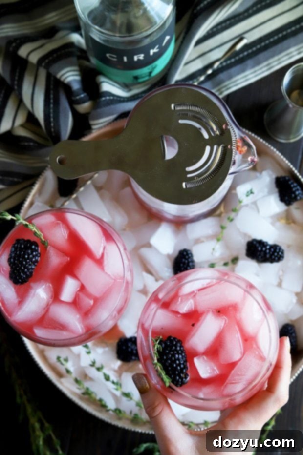 Picking up a blackberry thyme cocktail in a large wine glass