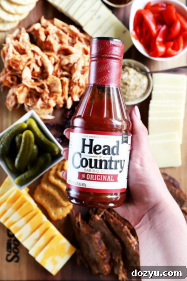 A hand holding a bottle of Head Country Bar-B-Q sauce, ready to be poured.
