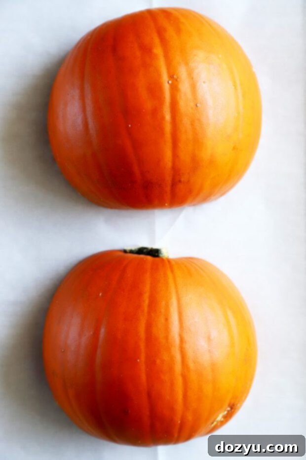 Pie pumpkin halves ready to bake on a parchment-lined baking sheet