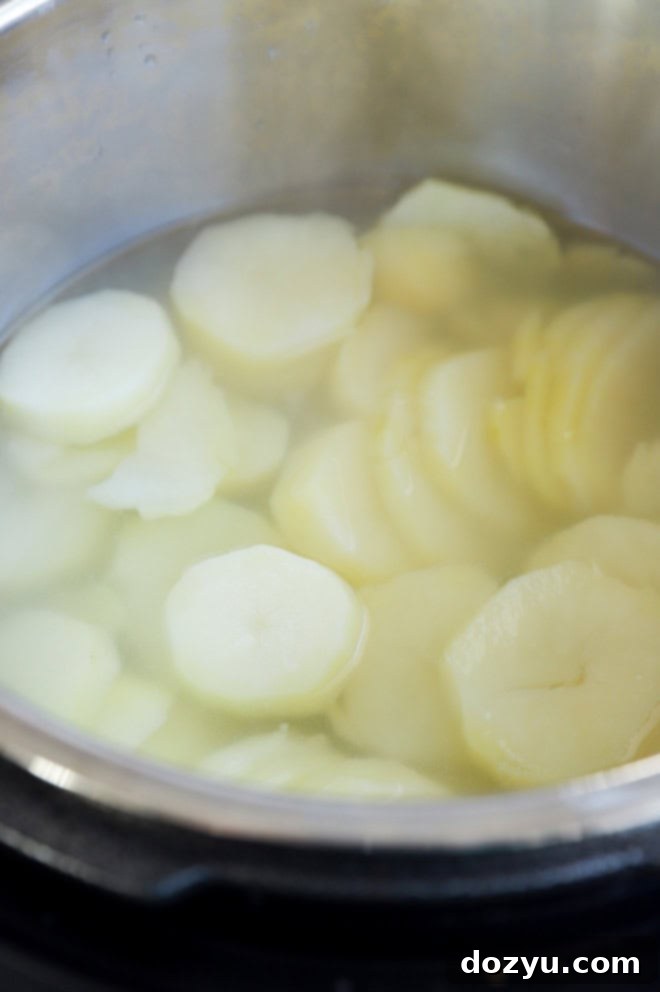 Sliced potatoes cooking in an Instant Pot with water.