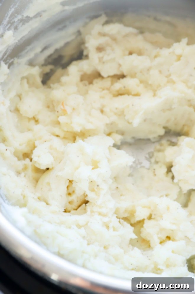 A bowl of creamy Instant Pot Mashed Potatoes, garnished with fresh herbs.