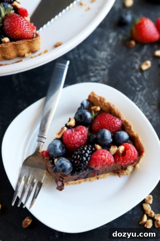 A close-up photo of a slice of ganache tart with a bite taken out, highlighting the smooth texture of the chocolate and the flaky crust.