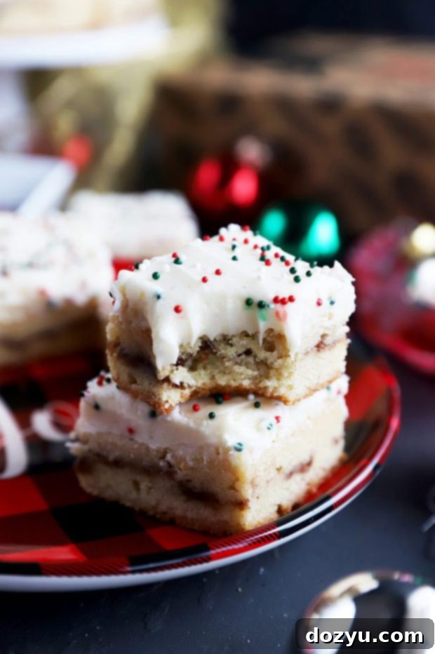 Stacked, frosted chewy snickerdoodle cookie bars on a festive holiday plate with cinnamon garnish