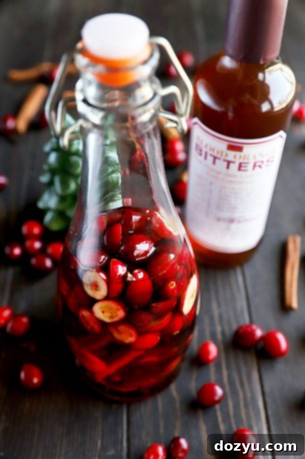 Infused whiskey in a bottle with cranberries and cinnamon sticks