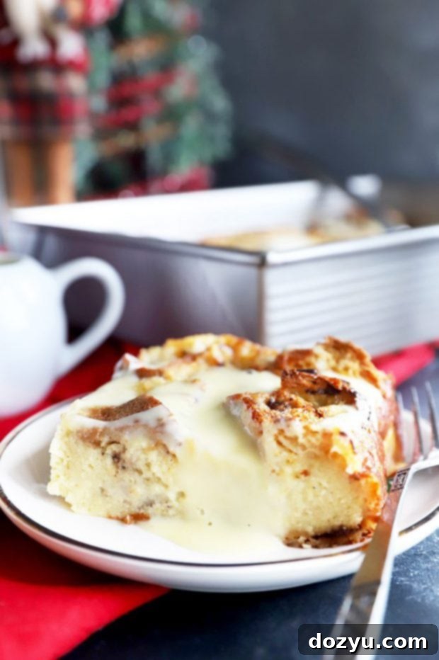 A close-up side view of a generous slice of Panettone Bread Pudding, showing its moist, tender interior and golden crust, ready for a drizzle of crème anglaise.