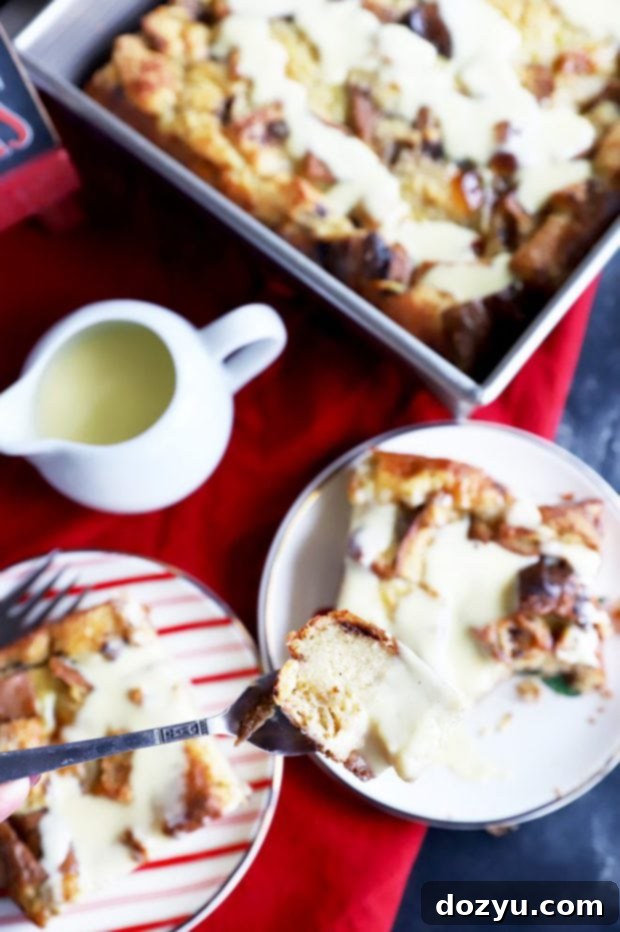 A single fork piercing a piece of Panettone Bread Pudding, revealing its soft, custardy interior and a generous coating of crème anglaise.