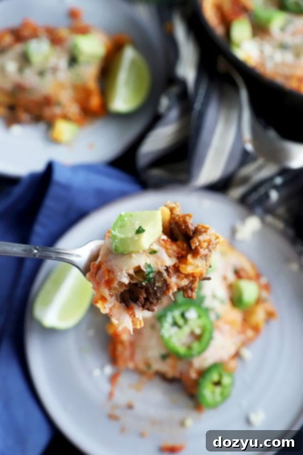 A fork taking a bite of short ribs, cheese, and tortillas