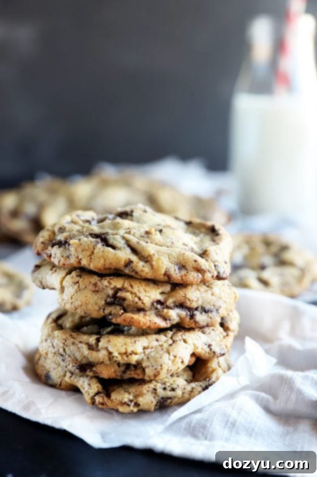 Stacked sea salt dark chocolate pistachio cookies next to a glass of milk