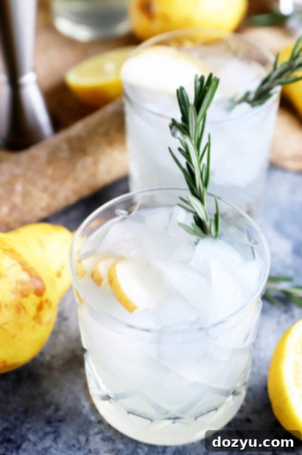 Aromatic Pear Rosemary Gin and Tonic 3 Elegant side view of Pear Rosemary Gin and Tonic cocktails on a wooden surface.