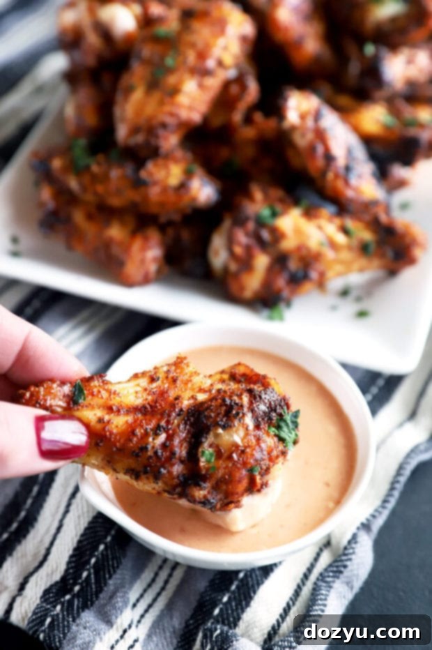 Dry rub chicken wing being dipped in sauce