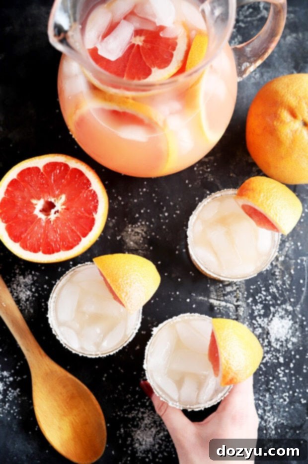 Smoky Mezcal Paloma Punch 3 Overhead view of a hand holding a glass of Mezcal Paloma Punch