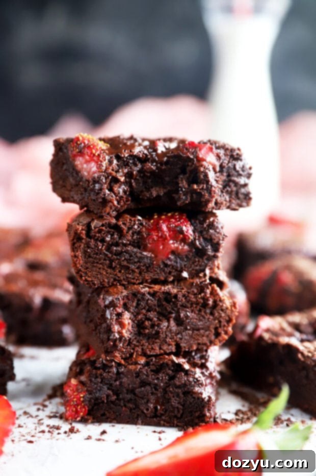 Velvet Berry Chocolate Brownies 2 Bite out of a chocolate strawberry brownie photo showcasing its gooey texture and fresh strawberry chunks