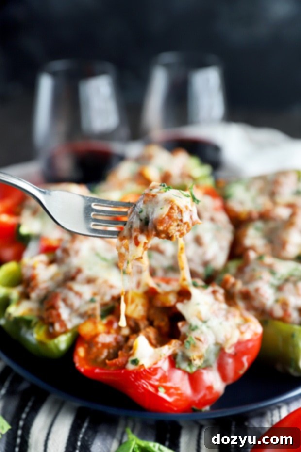 A close-up of a fork pulling cheesy filling from a Spicy Italian Stuffed Pepper