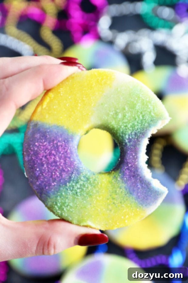 A hand holding a perfectly baked King Cake Cookie, showcasing its thick, soft texture and colorful sprinkles.