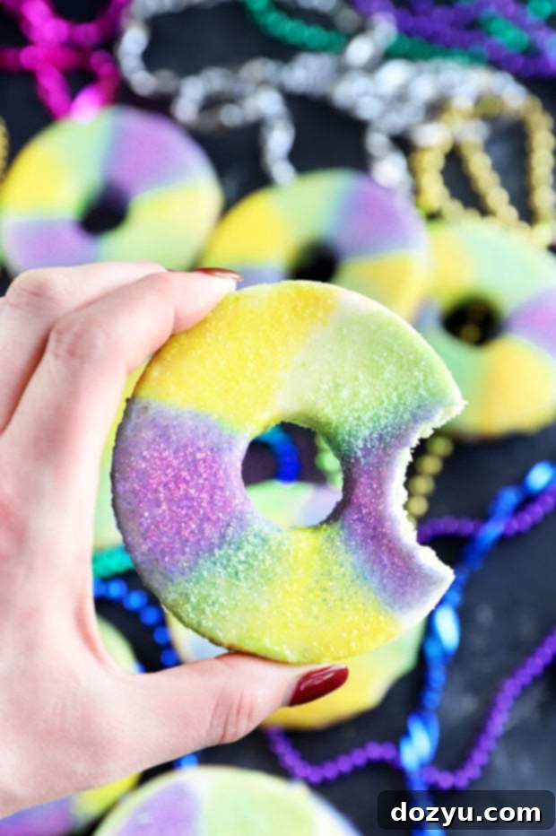 A hand reaching for a single decorated King Cake Cookie from a platter.