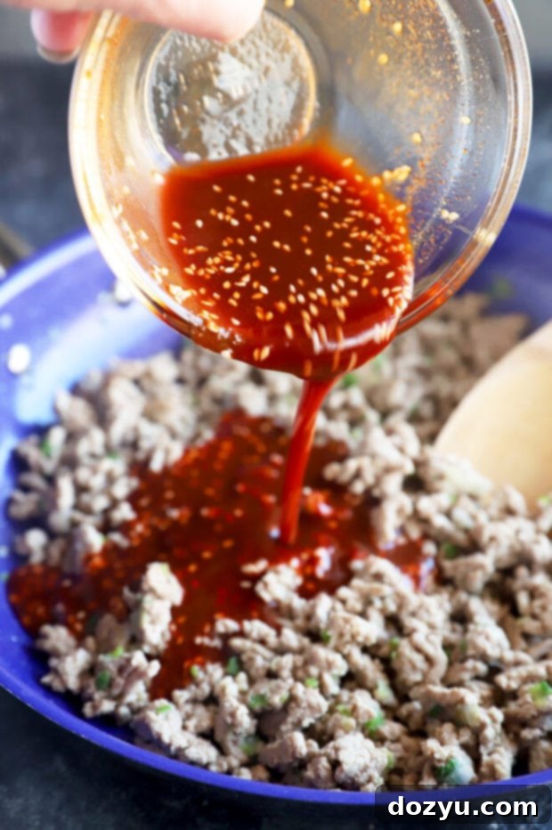 Pouring Korean sauce onto ground turkey in a skillet