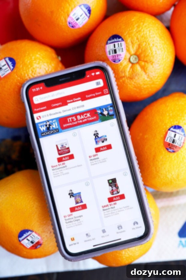 A smartphone screen displaying the Safeway mobile app, with fresh Sunkist oranges in focus in the background, illustrating the ease of finding these seasonal fruits.