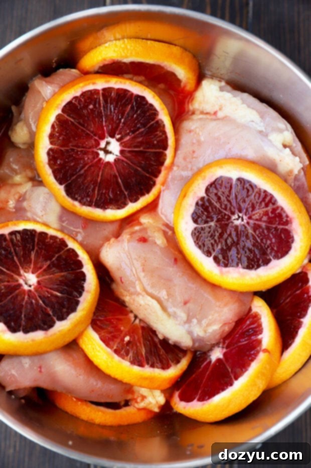 Sunkist Blood Orange Honey Ginger Chicken, along with sliced blood oranges, marinating in a mixing bowl, ready for baking.