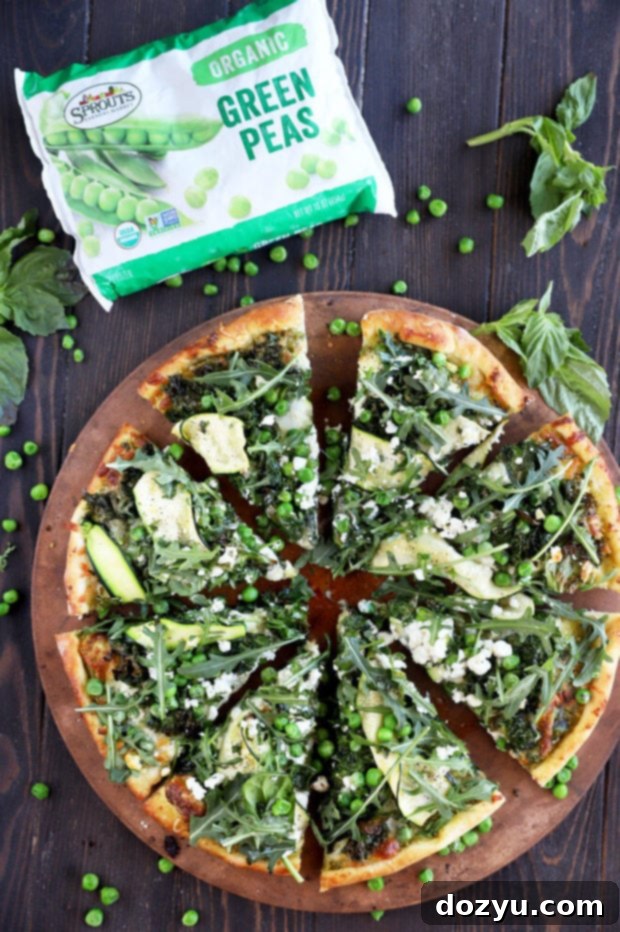 Freshly baked Pesto Green Pizza on a pizza stone, showcasing crispy kale, melted cheese, and a vibrant green pesto base.
