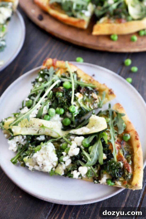 A single slice of Pesto Green Pizza on a small plate, emphasizing the vibrant green toppings and perfectly baked crust.