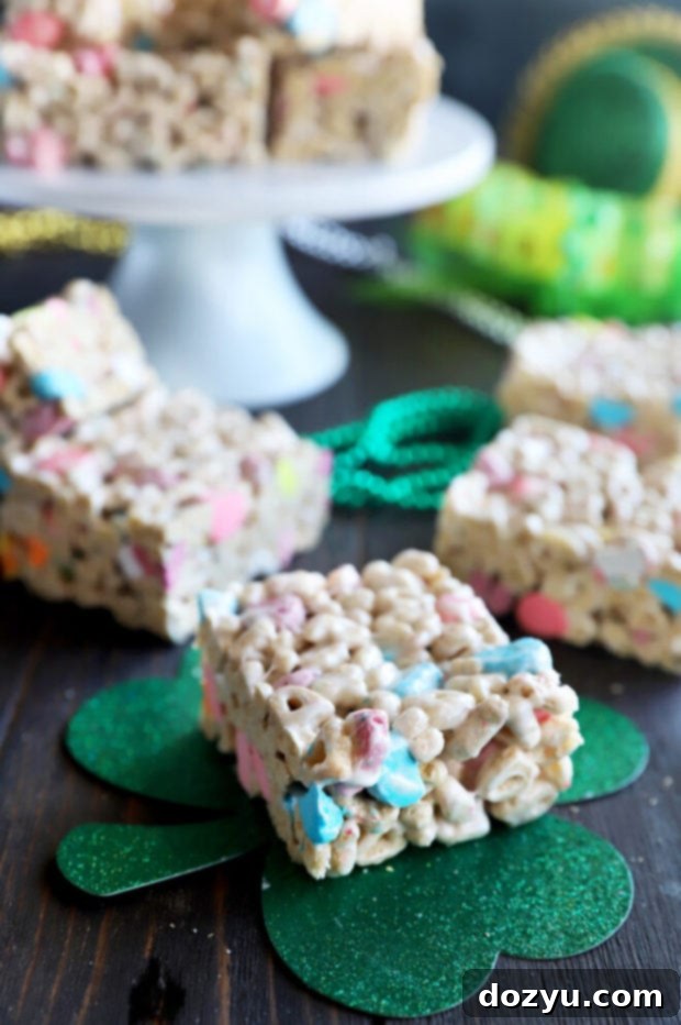 Close-up image of a tray of freshly made Lucky Charms cereal treats, highlighting their gooey texture and vibrant marshmallows.