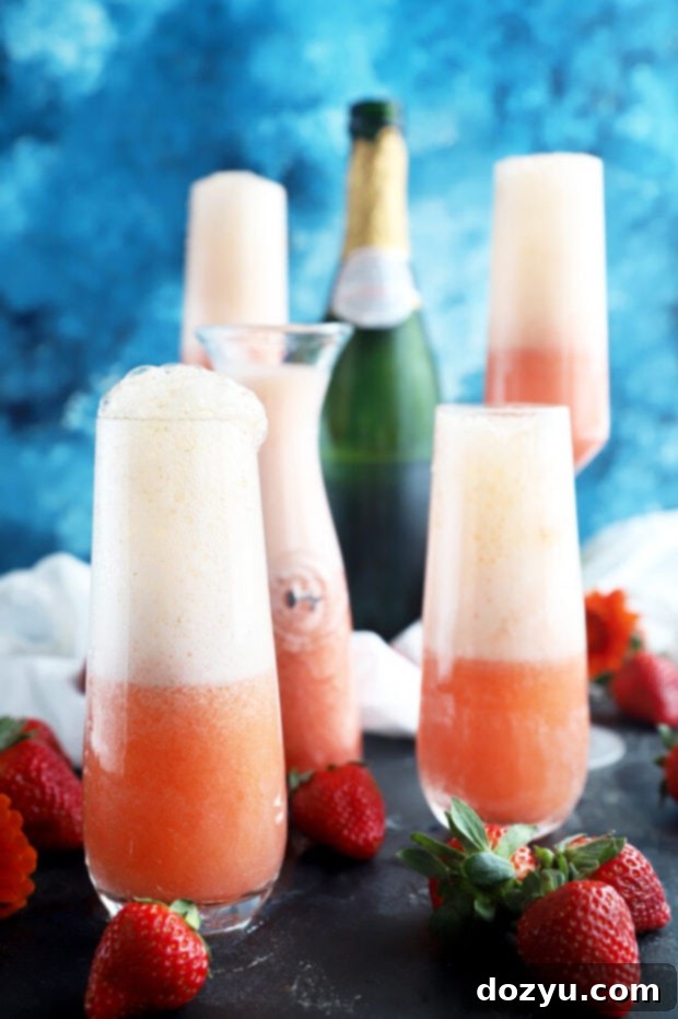 Strawberry Sparkler 3 Two strawberry mimosas in champagne flutes, garnished with fresh strawberries