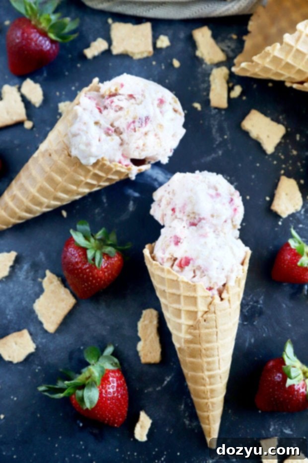Three ice cream cones, each with generous scoops of Strawberry Cheesecake Ice Cream, presented on a rustic wooden surface, highlighting the various toppings.
