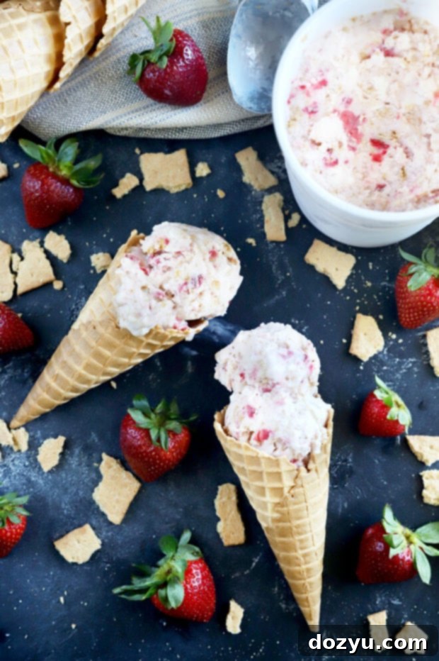 Several scoops of Strawberry Cheesecake Ice Cream served in waffle cones, demonstrating the varying sizes of graham cracker pieces and luscious strawberry swirls.