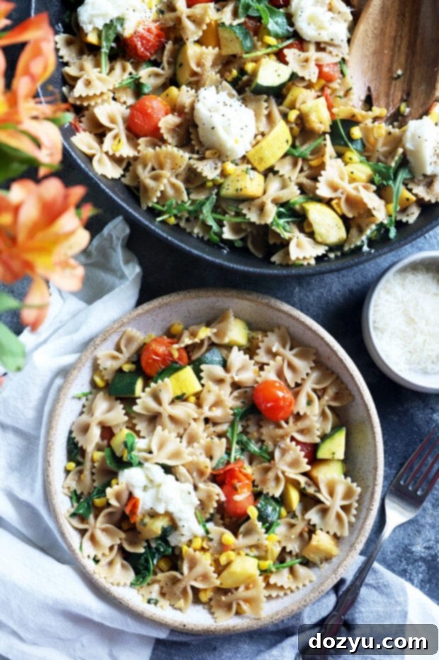 Overhead shot of farmer's market pasta served in bowls on a table with flowers, creating a lovely summer dining scene.