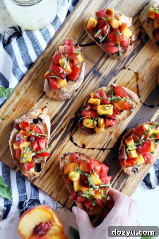 Overhead photo of a hand reaching for a piece of bruschetta, showcasing the vibrant colors of the topping.