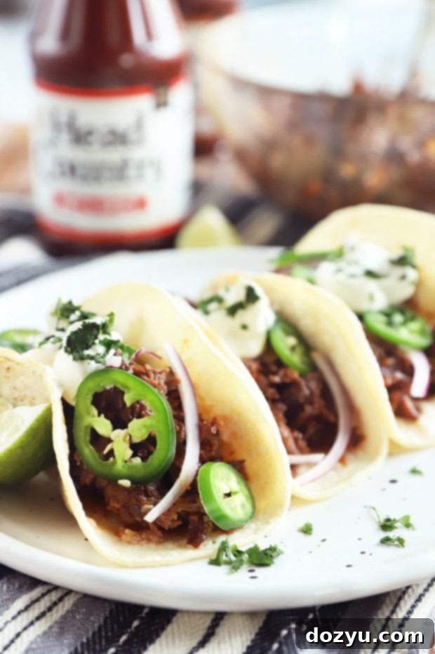 Side angle photo of beef tacos filled with shredded BBQ short ribs