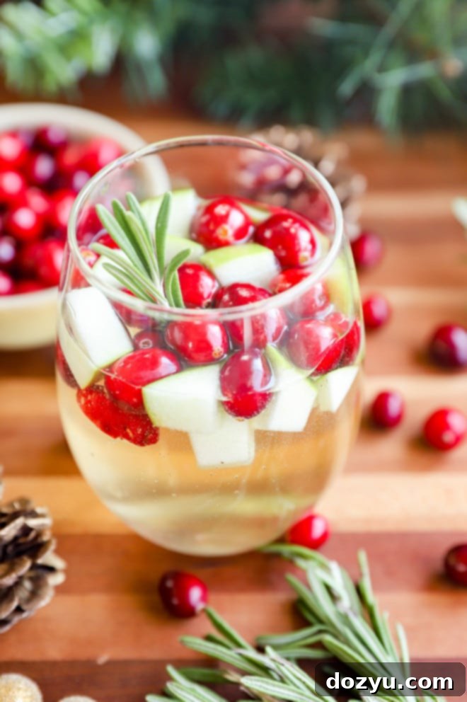 A beautiful glass of Christmas Sangria garnished with fresh rosemary and cranberries