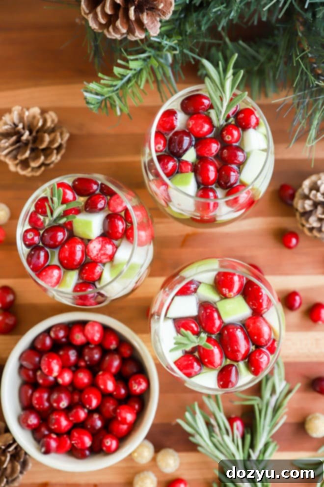 Two glasses of Christmas Sangria beautifully garnished with fresh rosemary sprigs and floating cranberries