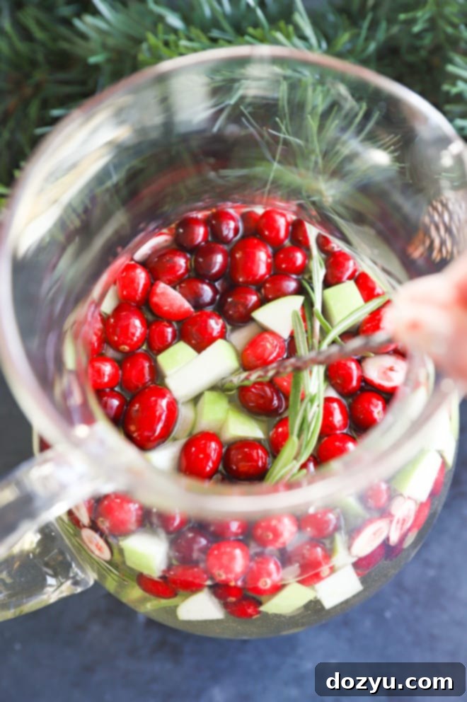 Stirring Christmas Sangria ingredients in a large pitcher with a wooden spoon