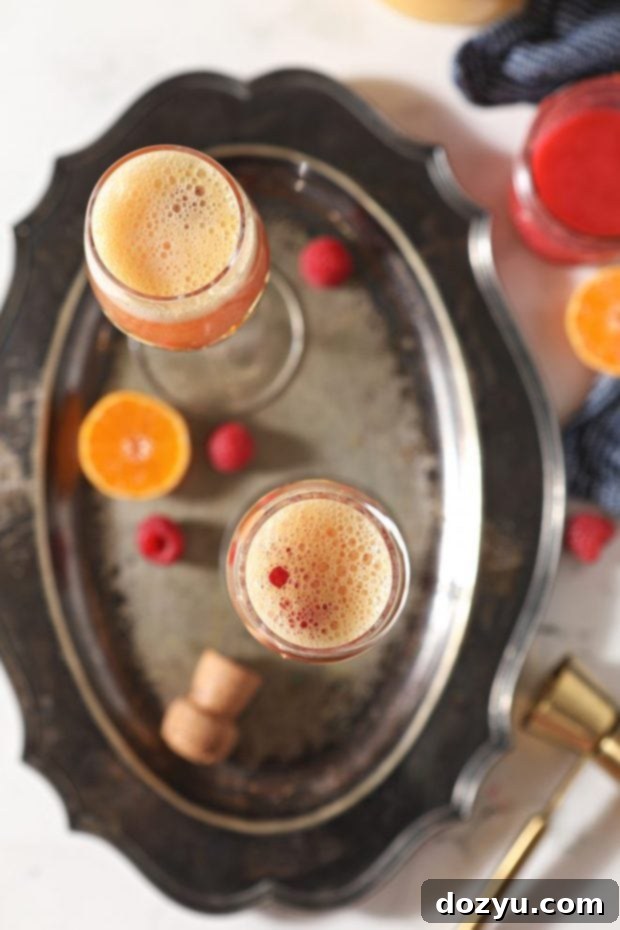 Brunch Bliss Raspberry Mimosa 3 Overhead image of raspberry mimosas on a platter, garnished with fresh raspberries and mint