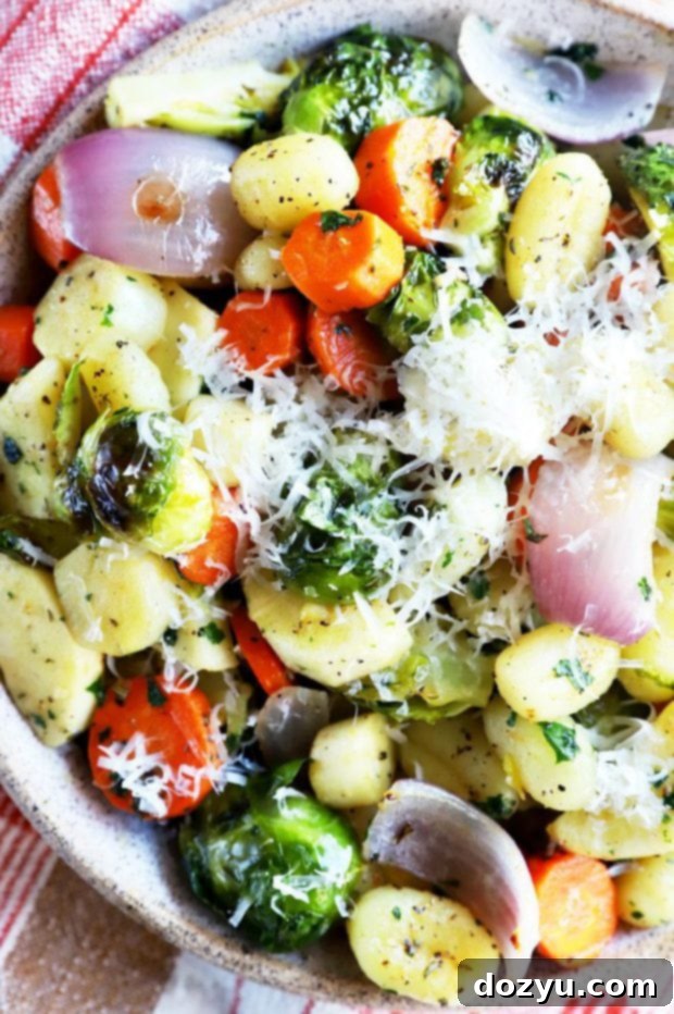 Ingredients for sheet pan gnocchi laid out: gnocchi, various winter vegetables, fresh herbs, and olive oil.
