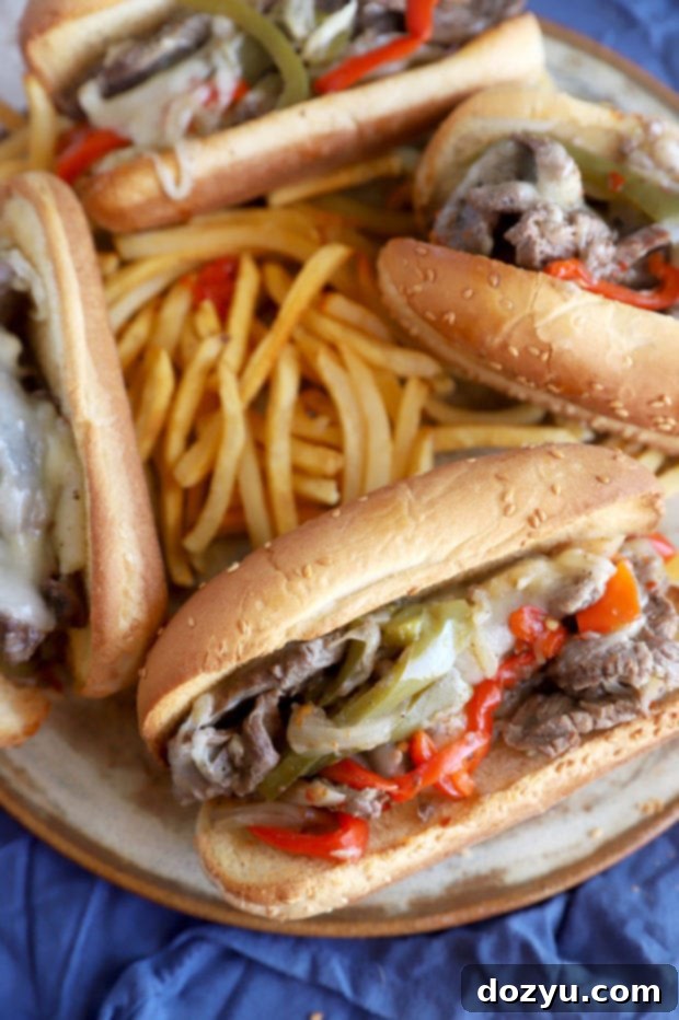 Plates of Instant Pot Philly Cheesesteaks served with golden fries, showcasing the melted cheese and tender ingredients.