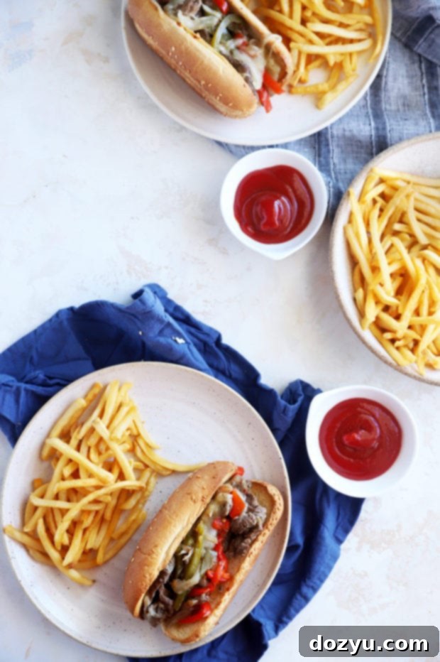 Two plates featuring delectable Instant Pot Philly Cheesesteaks and crispy fries, ready for a satisfying meal.