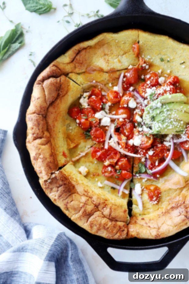 Savory Dutch Baby Bake 7 Overhead view of a sliced savory Dutch Baby pancake in a skillet, topped with fresh ingredients.