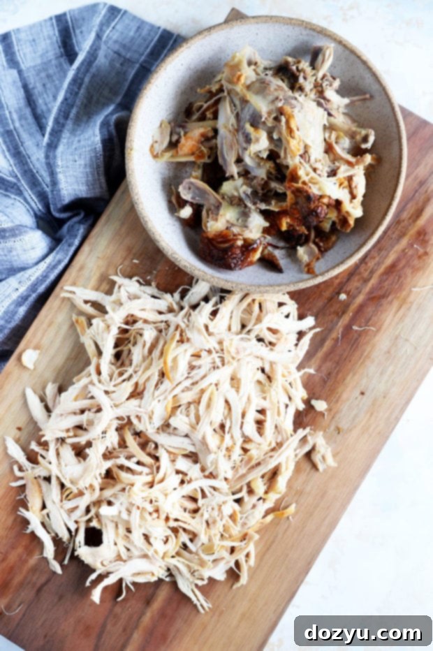 Overhead shot of shredded pickle brined chicken in a bowl with bones on the side