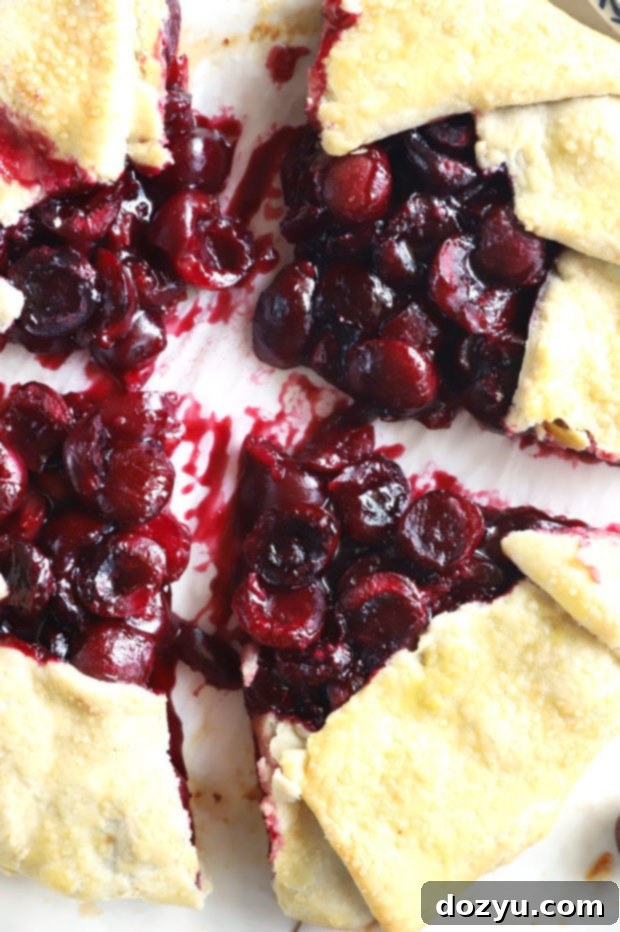 A whole Brandy Cherry Galette cooling on a wooden board, highlighting its rustic golden crust and juicy filling