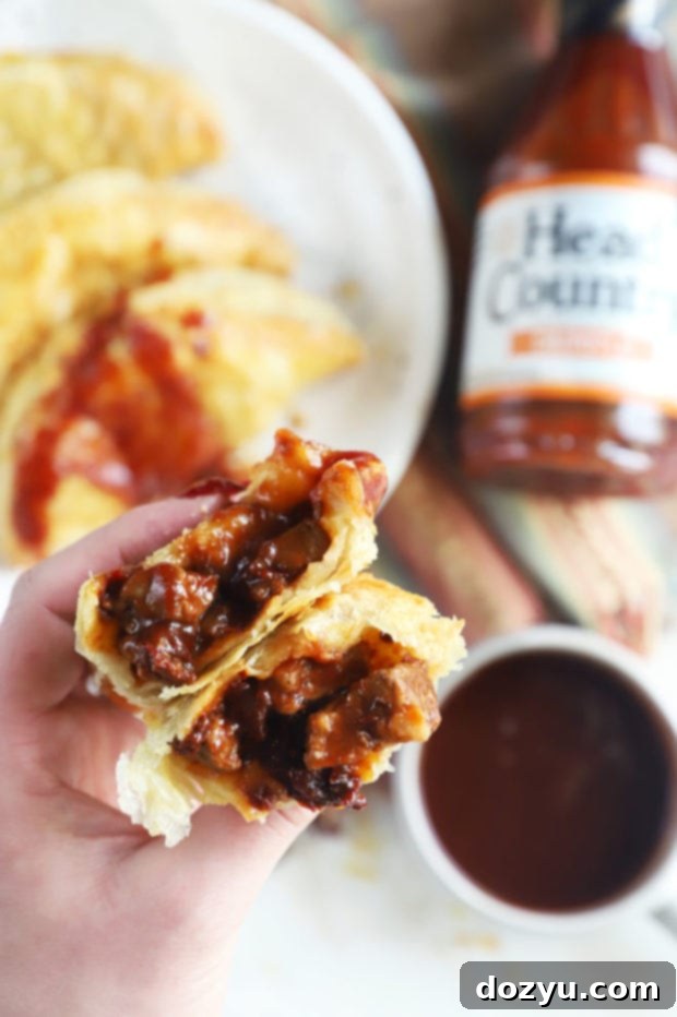 Hand holding golden brown air fryer empanadas with a smoky steak filling