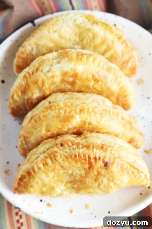Two perfectly golden air fryer empanadas on a rustic wooden surface