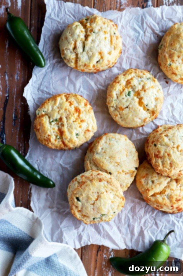 Overhead shot of several golden-brown Jalapeño Cheddar Biscuits arranged artfully, highlighting their texture and the specks of jalapeño and cheese.