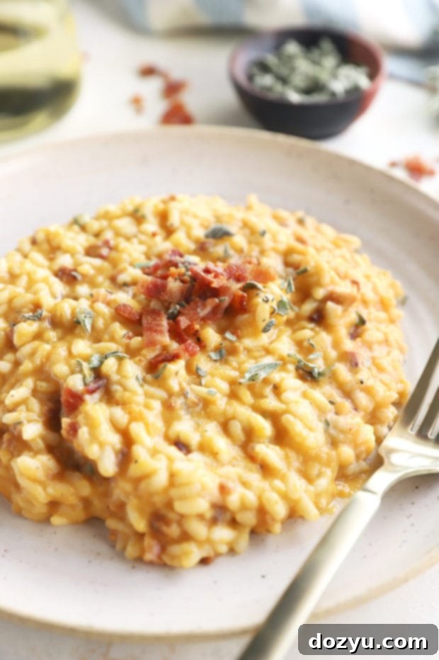 A bowl of Bacon Butternut Squash Risotto garnished with fresh sage and a spoon, ready to be enjoyed.