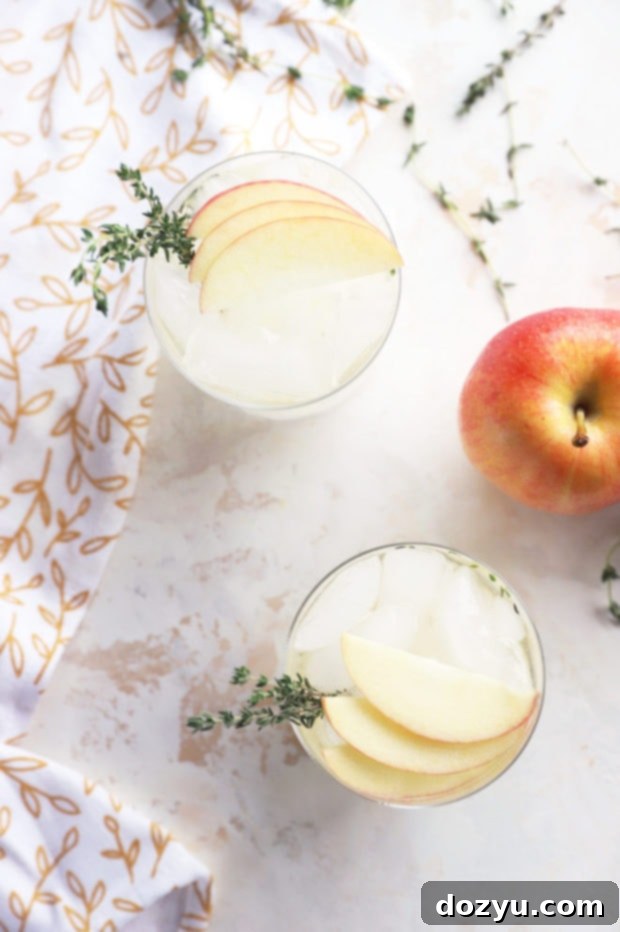 Overhead photo of three Thyme Apple Gin and Tonics, perfectly garnished with apple slices and thyme sprigs, ready for a fall celebration