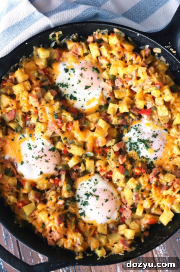 Close-up of baked Southwestern Ham Hash in a skillet, showcasing runny egg yolks, melted cheese, and fresh cilantro garnish.