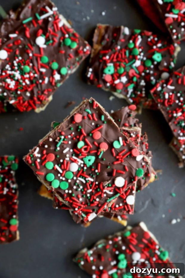 Overhead image of freshly made Christmas crack candy on a baking sheet, featuring melted chocolate and festive sprinkles on top.