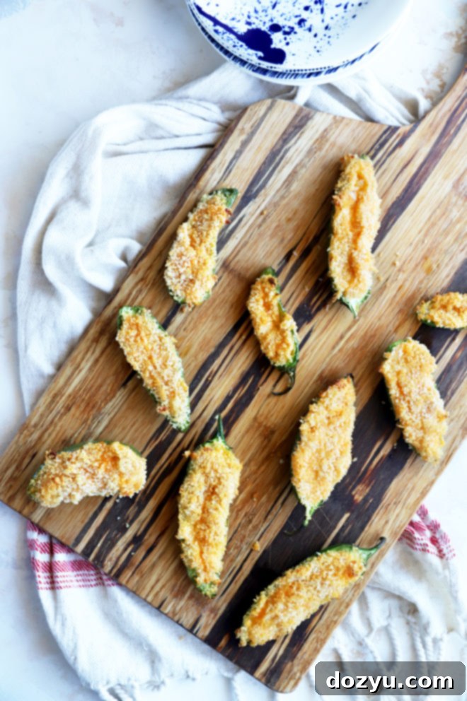 Overhead image of jalapeno poppers with crispy topping on a wooden board
